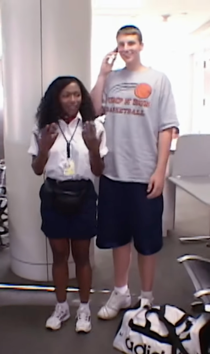 Tall passenger compared to airline crew illustrating body size differences affecting seat fit